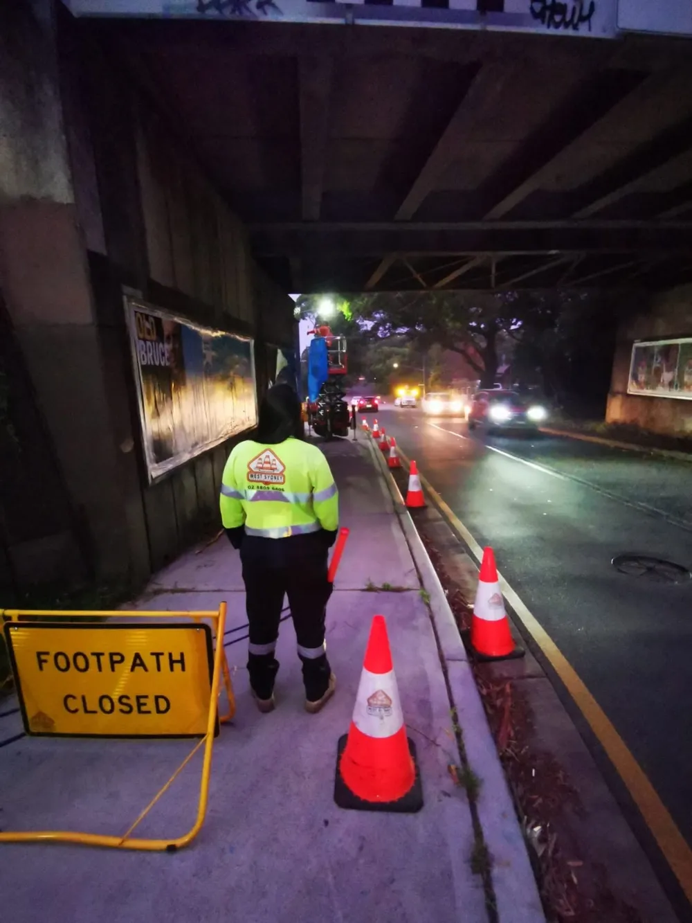Traffic controller in hi-vis managing a footpath closure at night
